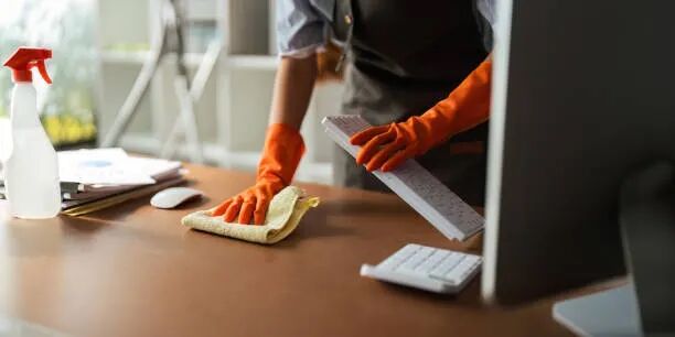 Pulizia di un ufficio moderno con scrivanie e computer